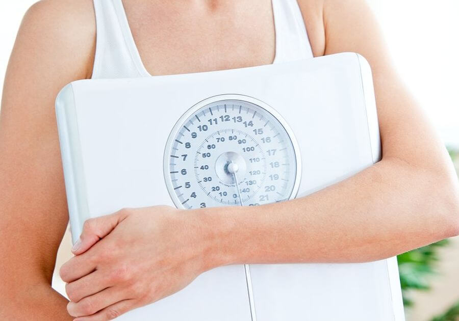 Close-up of a hispanic woman holding a scale in her living-room at home-1